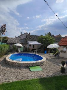 a swimming pool in a yard with umbrellas at Apartman Katarina Bački Monoštor in Bački Monoštor