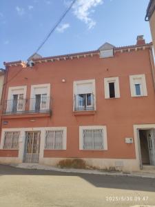 an orange building with barred windows on a street at Apartamentos Joli in Olivares de Duero