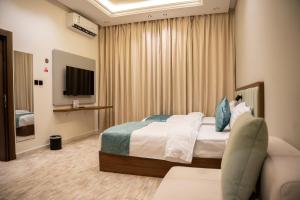 a hotel room with a bed and a television at فندف ألان للشقق الفندقية in Hail
