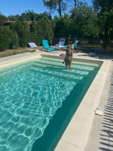 a young boy standing in a swimming pool at Logis de la Vau - Private pool - Quiet in Saint-Benoist-sur-Mer