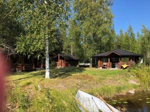 a cabin in the woods next to a body of water at Purola holiday cottage by the lake Kivijärvi in Kivijärvi