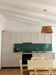 a kitchen with white cabinets and a table with chairs at Appartamento il Paguro a Cala Francese in La Maddalena