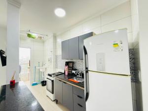 Refúgio Beira Mar Praia Grande في برايا جراندي: مطبخ أبيض مع ثلاجة ومغسلة