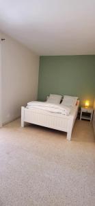 Cama blanca en habitación con pared verde en La Frégate Town Centre and Beach, en Le Grau-du-Roi