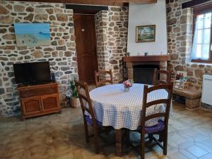ein Esszimmer mit Tisch und Kamin in der Unterkunft Les Roses Trémières in Trans