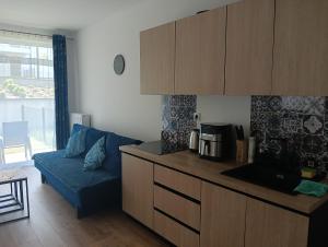 a kitchen with a blue couch in a living room at Apartament Fale Bałtyku in Kołobrzeg