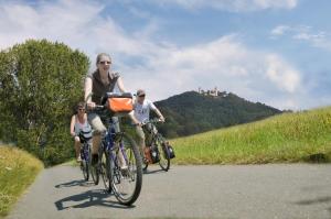 three people riding bikes down a road with a castle in the background at Design-Wohnungen by Ulrike Horster in Bensheim