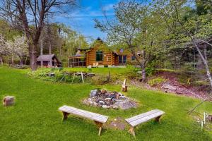 una cabaña de madera con una hoguera y dos bancos en Authentic Maine Log Cabin, en Greenville
