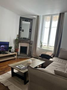 a living room with a couch and a table and a mirror at Appartement calme avec jardin in Nancy
