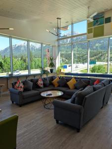 a living room with couches and a table and windows at Canmore Downtown Hostel in Canmore +29 photos