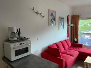 a living room with a red couch and a coffee maker at Gourette Euroneige Pied de piste - 6 personnes in Eaux-Bonnes