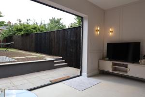 a living room with a television and a fence at NEW-BUILD Luxury House for Families and Contractors, NamisSuites Serviced Apartment - Farnborough in Farnborough