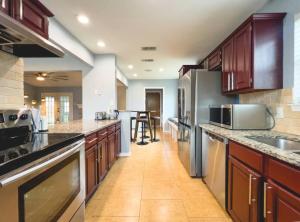 a large kitchen with wooden cabinets and stainless steel appliances at Plano Family Haven Cozy & Close To Everything! in Plano +62 photos