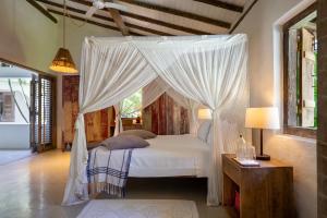 a bedroom with a canopy bed with white curtains at Vila Santo Rei Trancoso in Trancoso