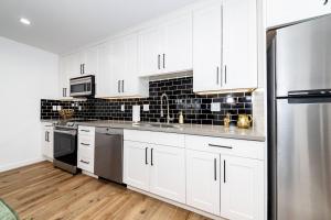 a kitchen with white cabinets and a stainless steel refrigerator at NoHo Home Near Universal Studios in Burbank