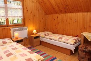 a bedroom with two beds in a wooden cabin at Chata Bielo in Liptovský Ján