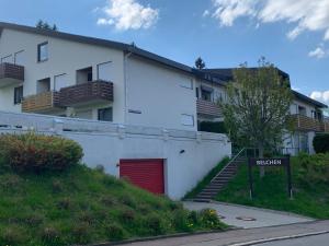 a white building with a red door and a red garage at Schwarzwaldliebe in Schonwald im Schwarzwald
