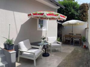 a patio with two chairs and a table with an umbrella at Charmantes Häuschen am Waldrand in Neustadt an der Weinstraße
