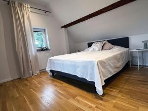 a bedroom with a bed with white sheets and a wooden floor at Charmantes Häuschen am Waldrand in Neustadt an der Weinstraße
