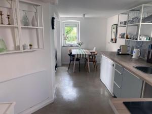 a kitchen with white cabinets and a table and a window at Charmantes Häuschen am Waldrand in Neustadt an der Weinstraße +7 photos
