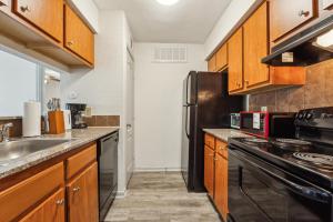 Una cocina con gabinetes de madera y un refrigerador negro. en Reserve 1331 I Spacious 1 Bed 1 Bath, en Houston 8 fotos más