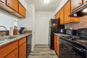 Una cocina con gabinetes de madera y un refrigerador negro. en Reserve At Westwood 2192 I Spacious 1 Bed 1 Bath, en Houston