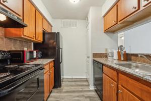 Una cocina con gabinetes de madera y un refrigerador negro. en Reserve At Westwood 3131 I Spacious 1 Bed 1 Bath, en Houston 8 fotos más