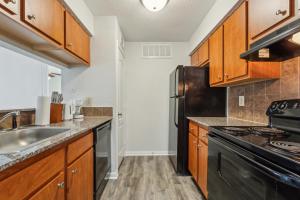 Una cocina con gabinetes de madera y un refrigerador negro. en Reserve At Westwood 3149 I Spacious 1 Bed 1 Bath, en Houston