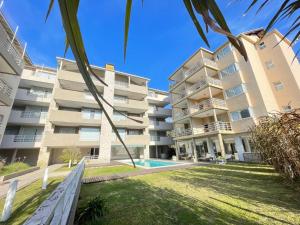 Un edificio de apartamentos con piscina y palmeras. en Brisa Marina Apart Hotel, en Pinamar