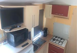 a small kitchen with a television and a stove at Mobil home paisible in Saint-Chéron