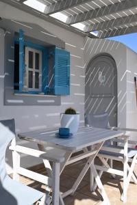 Ein Tisch und Stühle auf einer Terrasse mit blauen Fensterläden in der Unterkunft Koukida House in Donousa