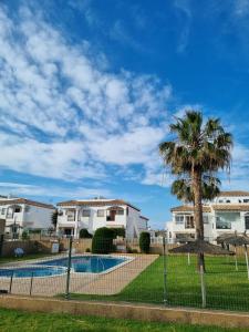 ein Zaun mit einer Palme vor Häusern in der Unterkunft Amanecer Costero in Orihuela