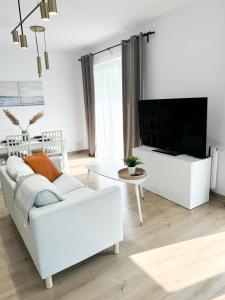 a living room with a white couch and a tv at Apartament Nikola in Władysławowo