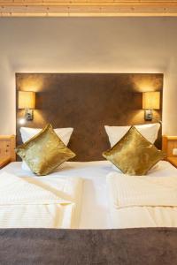 a bedroom with a white bed with gold pillows at Naturhotel Hüttenwirt im Grossarltal in Hüttschlag