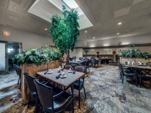un restaurante con mesas, sillas y plantas en Heritage Inn Hotel & Convention Centre - Cranbrook, en Cranbrook