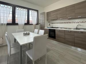 a kitchen with a white table and white chairs at Case Raggio di Sole in Siniscola
