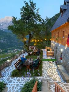 two people sitting in chairs on a patio near a building at Guesthouse Bec Villi in Theth