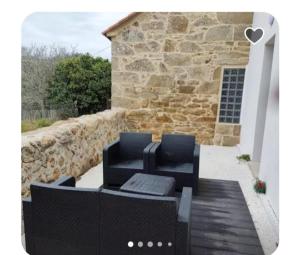 un patio avec un canapé noir et un mur en pierre dans l'établissement Casa Carreta, à Serres