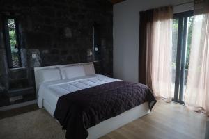 a bedroom with a bed and a large window at Casas do Caminho Novo in São Roque do Pico