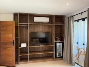 a living room with a entertainment center with a television at Maluhia Ilhabela 4 in Ilhabela