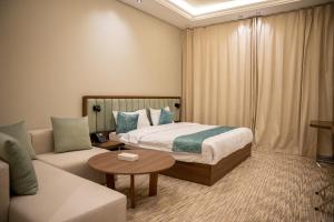 a hotel room with a bed and a couch at الان للشقق المخدومة in Hail