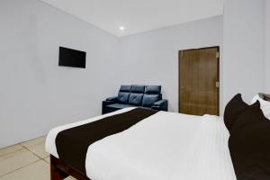 a bedroom with a bed and two blue chairs at HOTEL O V3 GRAND in Warangal
