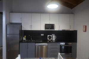 a kitchen with white cabinets and stainless steel appliances at Casas do Caminho Novo in São Roque do Pico
