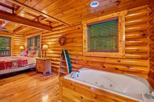 een blokhutbadkamer met een bad en een bed bij Mountain Magic Holiday home in Gatlinburg +44 foto's