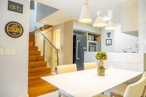 a kitchen and dining room with a white table and chairs at Duplex no In Mare Bali by Qavi in Granja Beira Mar