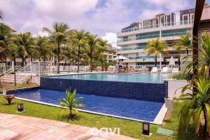 a swimming pool with palm trees in front of a building at Duplex no In Mare Bali by Qavi in Granja Beira Mar