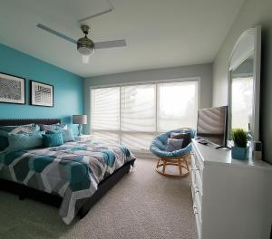 a bedroom with a bed and a chair and a window at Blue By The Bay in Panama City Beach