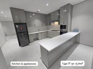 アル・コバールにあるNesmat Albaharの白いカウンターと冷蔵庫、家電製品を備えたキッチン