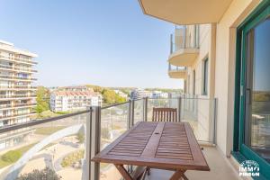 a wooden table on a balcony with a view of a city at Europan A0502 Esplanade, stijlvol en vlakbij het strand in De Panne