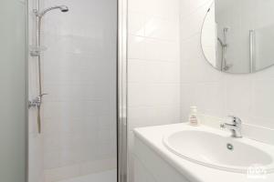 a white bathroom with a sink and a mirror at Europan A0502 Esplanade, stijlvol en vlakbij het strand in De Panne +8 photos
